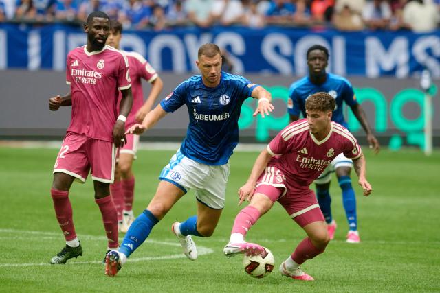 16 August 2026, North Rhine-Westphalia, Gelsenkirchen: (L-R) Real Madrid's Antonio Ruediger, Schalke 04's Edin Dzeko, and Real Madrid's Jorge Cestero in action during a friendly soccer match between FC Schalke 04 and Real Madrid CF at VELTINS-Arena, held to celebrate the stadium's 25th anniversary. Photo: Bernd Thissen/dpa - IMPORTANT NOTICE: Bundesliga and DFB regulations prohibit any use of photographs as image sequences and/or quasi-video.