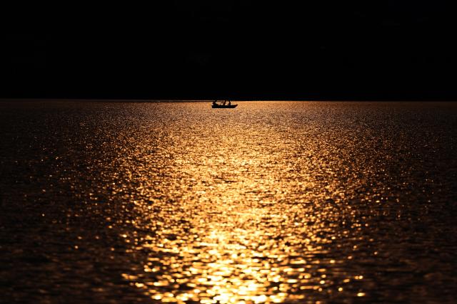 16 August 2026, Bavaria, Fuessen: Anglers row a boat across Lake Hopfensee during the sunset. Photo: Karl-Josef Hildenbrand/dpa