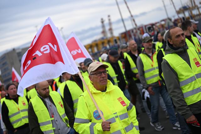18 August 2026, Bremen, Bremerhaven: Workers at the Port of Bremerhaven stand together at a Verdi rally held in conjunction with the warning strike. The union is currently negotiating with the employers' association ZDS over the wages of port workers. The employers' latest offer was rejected by the workers. Photo: Sina Schuldt/dpa