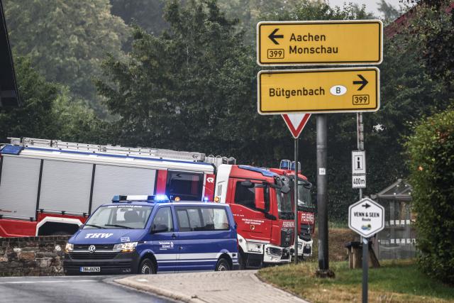 18 August 2026, North Rhine-Westphalia, Monschau: Fire department and Technical Relief Service (THW) emergency vehicles are parked along the roadside in the Kalterherberg district of the Aachen metropolitan region. In the Hohes Venn nature reserve in Belgium, the battle against the wildfires continues. German emergency responders are also involved, operating out of the Eifel town of Monschau. Photo: Oliver Berg/dpa