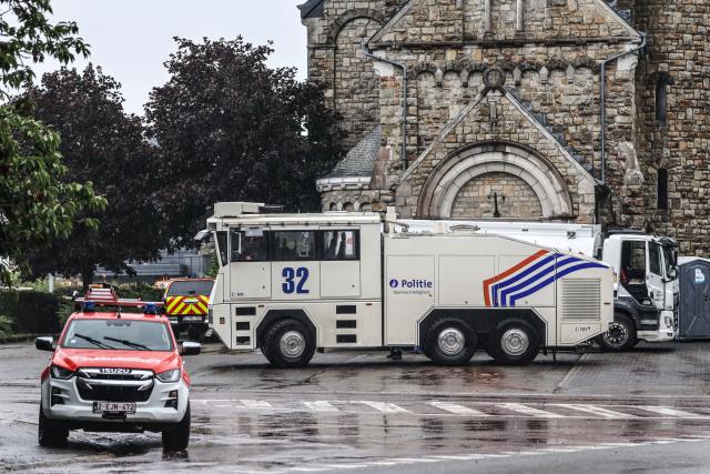 18 August 2026, North Rhine-Westphalia, Monschau: A Belgian police water cannon is parked in front of St. Wendelin Church in the Surbrot neighborhood. In Belgium's High Fens Nature Reserve, the battle against the wildfires continues. German emergency responders, operating out of the Eifel town of Monschau, are also involved. Photo: Oliver Berg/dpa