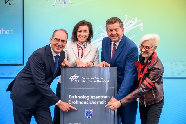 18 August 2026, Saxony-Anhalt, Hecklingen: Alexander Dobrindt (L-R) German Minister of the Interior; Dorothee Baer, German Minister of Research, Technology, and Space; Sven Schulze, Minister-President of Saxony-Anhalt, and Anke Kaysser-Pyzalla, Chairwoman of the Executive Board of the German Aerospace Center (DLR), open the Technology Center for Drone Safety and unveil the commemorative plaque bearing the institution's name. The Technology Center for Drone Safety is located at the DLR site in the Cochstedt district. Photo: Klaus-Dietmar Gabbert/dpa