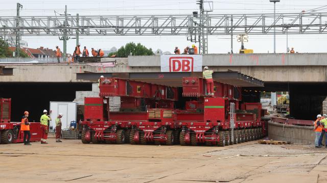 18 August 2026, Thuringia, Erfurt: A self-propelled modular transporter is positioned beneath the bridge during the demolition of a 38-meter-long, 1,800-metric-ton section of the bridge. Inspections revealed that a component of the railroad overpass, built in the 1970s, may be affected by stress corrosion cracking, so it is being completely replaced. Photo: Bodo Schackow/dpa