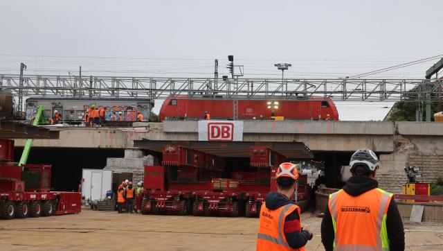 18 August 2026, Thuringia, Erfurt: A self-propelled modular transporter is positioned beneath the bridge during the demolition of a 38-meter-long, 1,800-metric-ton section of the bridge. Inspections revealed that a component of the railroad overpass, built in the 1970s, may be affected by stress corrosion cracking, so it is being completely replaced. Photo: Bodo Schackow/dpa