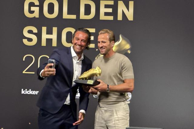 19 August 2026, Bavaria, Munich: Bayern Munich's Harry Kane takes a selfie with Italian former footballer Luca Toni, who presented him with the "Golden Boot" award, at the club museum in the Allianz Arena. Photo: Christoph Lother/dpa