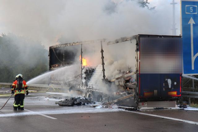 19 August 2026, Baden-Württemberg, Schriesheim: Firefighters extinguish a fire on a semi-trailer on the highway. Following a truck fire, Highway 5 near Schriesheim was temporarily closed in both directions; it was fully reopened this morning. According to police, the truck suddenly caught fire on Wednesday evening after two tires had burst. Photo: Rene Priebe/dpa
