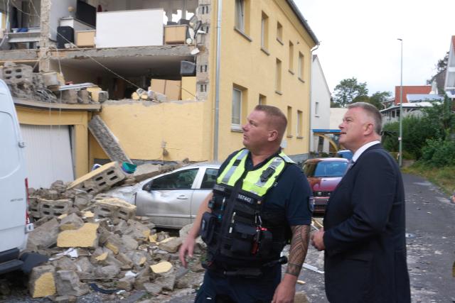 20 August 2026, Rhineland-Palatinate, Hoehr-Grenzhausen: Rhineland-Palatinate Minister President Gordon Schnieder (R) speaks with emergency responders in front of the damaged houses, after a thunderstorm hit the area leaving several houses severely damaged. Photo: Thomas Frey/dpa