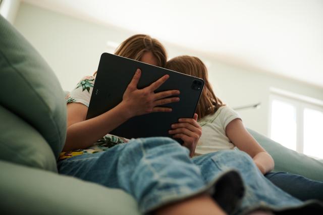FILED - 28 May 2022, Berlin: FILE PHOTO - Two sisters are sitting on the couch, looking at their parents' tablet. Photo: Annette Riedl/dpa