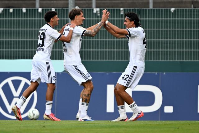 21 August 2026, North Rhine-Westphalia, Krefeld: (L-R) Eintracht Frankfurt's Ayoube Amaimouni-Echghouyab, Robin Koch and Can Uzun celebrate their second goal during the German DFB Cup first Round soccer match between SC St. Toenis 11/20 and Eintracht Frankfurt at the Grotenburg Stadium. Photo: Federico Gambarini/dpa - IMPORTANT NOTICE: Bundesliga and DFB regulations prohibit any use of photographs as image sequences and/or quasi-video.