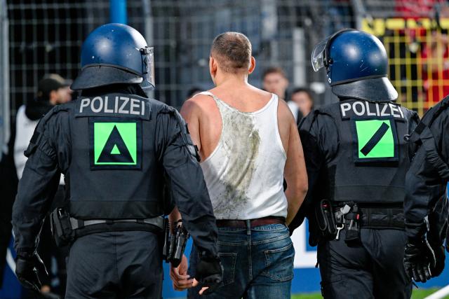 21 August 2026, Mannheim: A fan of SV Mannheim is being escorted away by police officers during the German DFB Cup first round soccer match between SV Waldhof Mannheim and 1. FC Kaiserslautern at the Carl-Benz-Stadion. . Photo: Uwe Anspach/dpa - IMPORTANT NOTICE: Bundesliga and DFB regulations prohibit any use of photographs as image sequences and/or quasi-video.