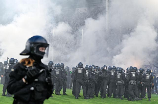 21 August 2026, Mannheim: Police officers stand in front of the SV Waldhof Mannheim fan section during the German DFB Cup first round soccer match between SV Waldhof Mannheim and 1. FC Kaiserslautern at the Carl-Benz-Stadion. . Photo: Uwe Anspach/dpa - IMPORTANT NOTICE: In accordance with the regulations of the Bundesliga and the DFB (German Football Association), it is prohibited to use or allow the use of photographs taken in the stadium and/or during the game in the form of sequential images and/or video-like photo series.