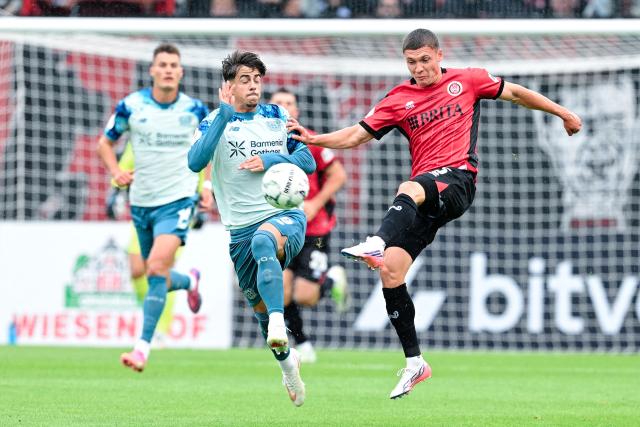 22 August 2026, Hesse, Wiesbaden: Leverkusen's Afonso Moreira (L) and Wiesbaden's Niklas May battle for the ball during the German DFB Cup first round soccer match between SV Wehen Wiesbaden and Bayer Leverkusen at BRITA-Arena. Photo: Uwe Anspach/dpa - IMPORTANT NOTICE: In accordance with the regulations of the Bundesliga and the German Football Association (DFB), it is prohibited to use or allow the use of photographs taken in the stadium and/or during the game in the form of sequential images and/or video-like photo sequences.