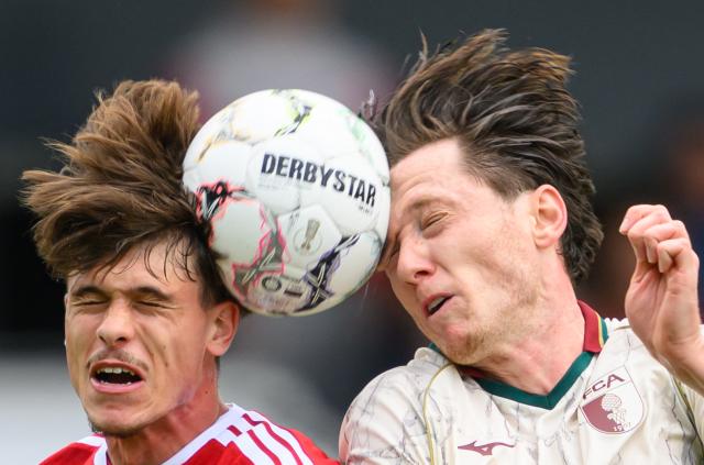 22 August 2026, Brandenburg, Cottbus: Energie Cottbus' Luca Erlein (L) and Augsburg's Michael Gregoritsch battle for the ball during the German DFB Cup first round soccer match between FC Energie Cottbus and FC Augsburg at LEAG Energie Stadium. Photo: Robert Michael/dpa - IMPORTANT NOTICE: In accordance with the regulations of the Bundesliga and the German Football Association (DFB), it is prohibited to use or allow the use of photographs taken in the stadium and/or during the game in the form of sequential images and/or video-like photo sequences.