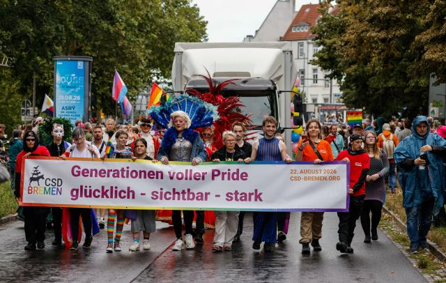 22 August 2026, Bremen: Participants in the Christopher Street Day (CSD) parade walk along Osterdeich behind a banner bearing the Pride Parade's motto: "Generations Full of Pride-Happy, Visible, Strong." Photo: Focke Strangmann/dpa