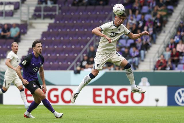 22 August 2026, Saxony, Aue: Hoffenheim's Andrej Kramaric heads the ball next to Erzgebirge Aue's Marcel Baer (L) during the German Cup (DFB Pokal) first round soccer match between Erzgebirge Aue vs TSG 1899 Hoffenheim at Erzgebirgsstadion. Photo: Jan Woitas/dpa - IMPORTANT NOTICE: Bundesliga and DFB regulations prohibit any use of photographs as image sequences and/or quasi-video.