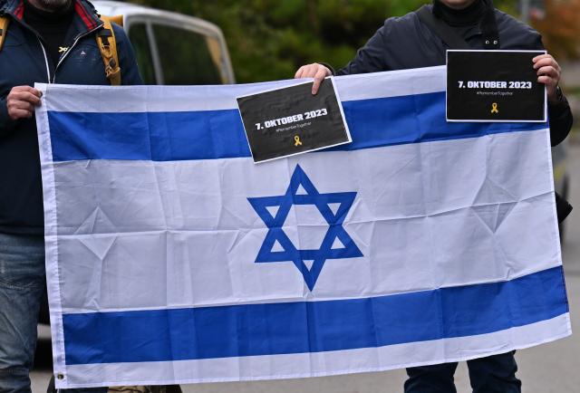 FILED - 07 October 2025, Thuringia, Erfurt: FILE PHOTO - People hold an Israeli flag during a commemorative event organized by the German-Israeli Society to mark the second anniversary of the October 7th Hamas led attack. Photo: Martin Schutt/dpa