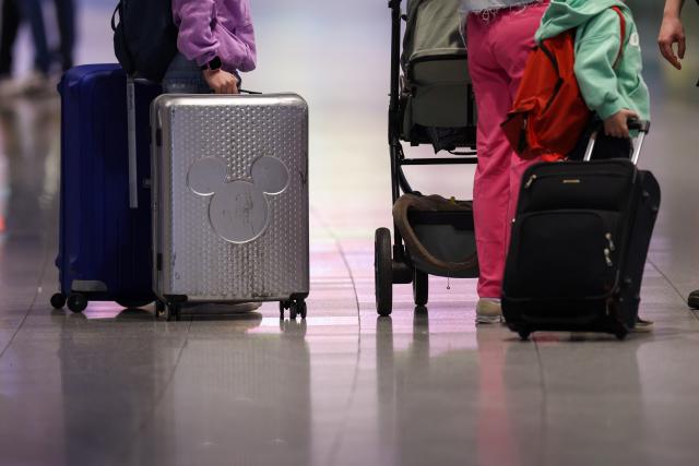 FILED - 28 March 2026, North Rhine-Westphalia, Duesseldorf: FILE PHOTO - A family stands with their luggage in a departure hall at Duesseldorf Airport. A traveler was stung by a scorpion that had been hiding in her jacket at Duesseldorf Airport. Photo: Christoph Reichwein/dpa