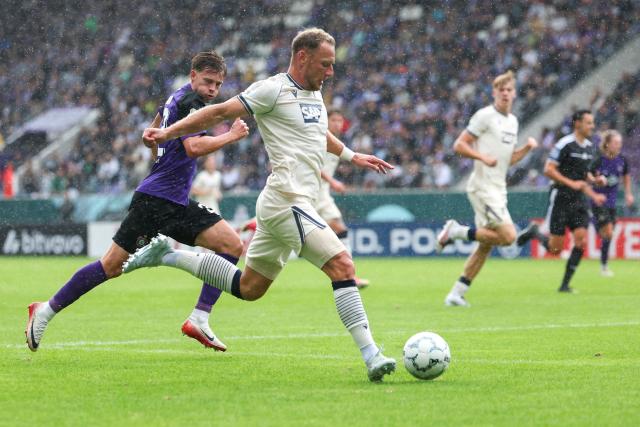 22 August 2026, Saxony, Aue: Hoffenheim's Vladimir Coufal (R) and Erzgebirge Aue's Maxim Burghardt battle for the ball during the German Cup (DFB Pokal) first round soccer match between Erzgebirge Aue vs TSG 1899 Hoffenheim at Erzgebirgsstadion. Photo: Jan Woitas/dpa - IMPORTANT NOTICE: Bundesliga and DFB regulations prohibit any use of photographs as image sequences and/or quasi-video.