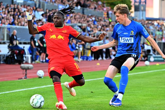 22 August 2026, Trier: Leipzig's Johan Bakayoko (L) and Eintracht Trier's Elia Dittrich battle for the ball during the German Cup (DFB Pokal) first round soccer match between Eintracht Trier and RB Leipzig at Moselstadion Photo: Harald Tittel/dpa - IMPORTANT NOTICE: Bundesliga and DFB regulations prohibit any use of photographs as image sequences and/or quasi-video.