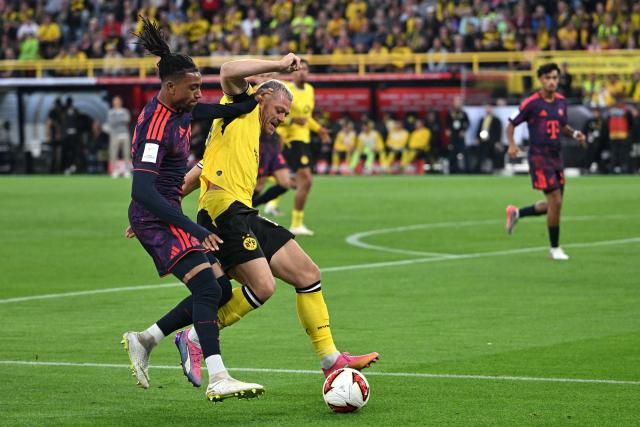 22 August 2026, Dortmund: Bayern Munich's Michael Olise and Borussia Dortmund's Julian Ryerson battle for the ball during the German Franz Beckenbauer Supercup soccer match between Borussia Dortmund and FC Bayern Munich at the Signal Iduna Park. Photo: Bernd Thissen/dpa - IMPORTANT NOTICE: Bundesliga and DFB regulations prohibit any use of photographs as image sequences and/or quasi-video.