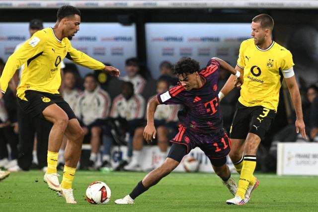 22 August 2026, Dortmund: Bayern Munich's Nathaniel Brown battles for the ball with Borussia Dortmund's Felix Nmecha and Waldemar Anton during the German Franz Beckenbauer Supercup soccer match between Borussia Dortmund and FC Bayern Munich at the Signal Iduna Park. Photo: Bernd Thissen/dpa - IMPORTANT NOTICE: Bundesliga and DFB regulations prohibit any use of photographs as image sequences and/or quasi-video.
