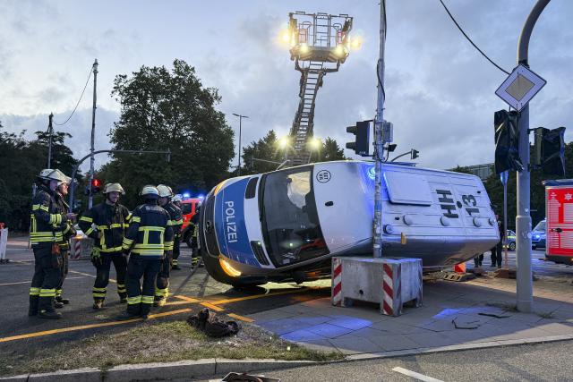 22 August 2026, Hamburg: Firefighters and police officers stand near an overturned police prisoner transport vehicle and an SUV, at the scene of a traffic accident in Hamburg. Photo: Christian Charisius/dpa