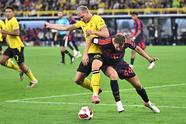 22 August 2026, Dortmund: Borussia Dortmund's Julian Ryerson and Bayern Munich's Josip Stanisic battle for the ball during the German Franz Beckenbauer Supercup soccer match between Borussia Dortmund and FC Bayern Munich at the Signal Iduna Park. Photo: Bernd Thissen/dpa - IMPORTANT NOTICE: Bundesliga and DFB regulations prohibit any use of photographs as image sequences and/or quasi-video.