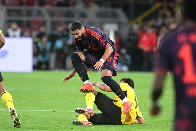 22 August 2026, Dortmund: Borussia Dortmund's Ramy Bensebaini fouls Bayern Munich's Ismael Saibari during the German Franz Beckenbauer Supercup soccer match between Borussia Dortmund and FC Bayern Munich at the Signal Iduna Park. Photo: Bernd Thissen/dpa - IMPORTANT NOTICE: Bundesliga and DFB regulations prohibit any use of photographs as image sequences and/or quasi-video.