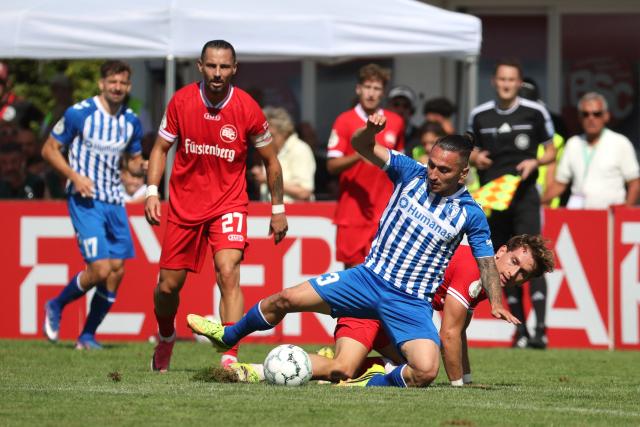 23 August 2026, Baden-Wuerttemberg, Bahlingen am Kaiserstuhl: Magdeburg's Baris Atik and Bahlinger's Holger Bux (R) battle for the ball during the German DFB Cup first round soccer match between Bahlinger SC and 1. FC Magdeburg at Kaiserstuhlstadion. Photo: Philipp von Ditfurth/dpa - WICHTIGER HINWEIS: Gemäß den Vorgaben der Bundesliga bzw. des DFB Deutscher Fußball-Bund ist es untersagt, in dem Stadion und/oder vom Spiel angefertigte Fotoaufnahmen in Form von Sequenzbildern und/oder videoähnlichen Fotostrecken zu verwerten bzw. verwerten zu lassen.