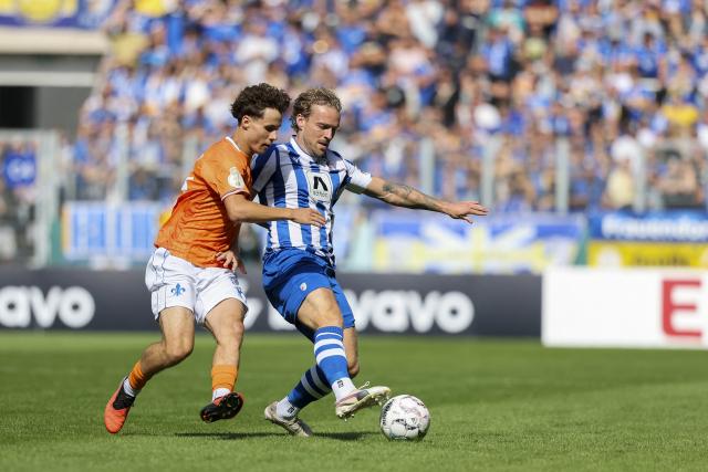 23 August 2026, Thuringia, Jena: Darmstadt's Manolo Merx (L) and Carl Zeiss Jena's Nils Butzen battle for the ball during the German DFB Cup first round soccer match between FC Carl Zeiss Jena and Darmstadt 98 at Ernst-Abbe-Sportfeld. Photo: Jan Woitas/dpa - WICHTIGER HINWEIS: Gemäß den Vorgaben der Bundesliga bzw. des DFB Deutscher Fußball-Bund ist es untersagt, in dem Stadion und/oder vom Spiel angefertigte Fotoaufnahmen in Form von Sequenzbildern und/oder videoähnlichen Fotostrecken zu verwerten bzw. verwerten zu lassen.