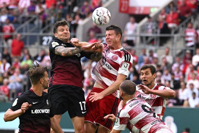 23 August 2026, North Rhine-Westphalia, Duesseldorf: Freiburg's Lukas Kuebler (L) and Fortuna Duesseldorf's Dominique Heintz battle for the ball during the German DFB Cup first round soccer match between Fortuna Duesseldorf and SC Freiburg at the Merkur Spiel-Arena. Photo: Federico Gambarini/dpa - WICHTIGER HINWEIS: Gemäß den Vorgaben der Bundesliga bzw. des DFB Deutscher Fußball-Bund ist es untersagt, in dem Stadion und/oder vom Spiel angefertigte Fotoaufnahmen in Form von Sequenzbildern und/oder videoähnlichen Fotostrecken zu verwerten bzw. verwerten zu lassen.