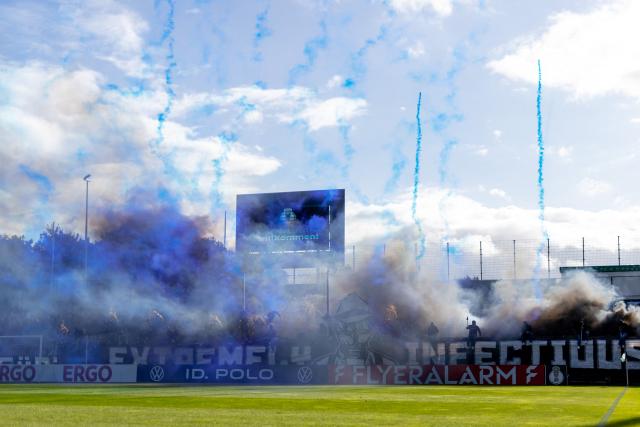 23 August 2026, Schleswig-Holstein, Luebeck: SC Paderborn 07 fans set off fireworks before the German DFB Cup first round soccer match between Phoenix Luebeck and SC Paderborn 07 at Dietmar-Scholze-Stadion an der Lohmuehle. Photo: Philipp Szyza/dpa - WICHTIGER HINWEIS: Gemäß den Vorgaben der Bundesliga bzw. des DFB Deutscher Fußball-Bund ist es untersagt, in dem Stadion und/oder vom Spiel angefertigte Fotoaufnahmen in Form von Sequenzbildern und/oder videoähnlichen Fotostrecken zu verwerten bzw. verwerten zu lassen.
