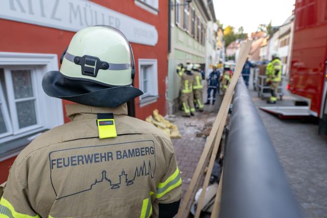 23 August 2026, Bavaria, Bamberg: Firefighters and THW rescue workers secure a house wall that has a large hole in it after a car cras. Photo: Pia Bayer/dpa
