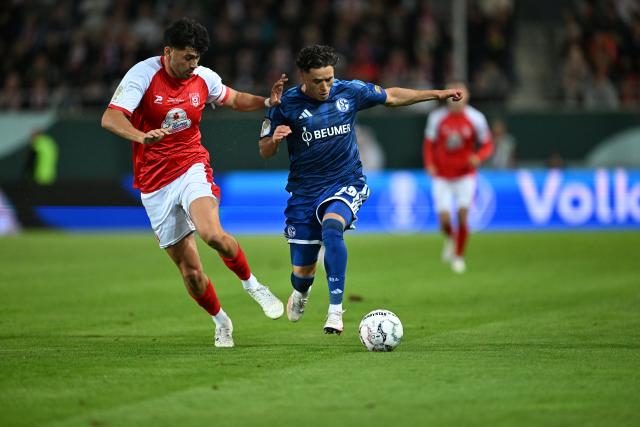 24 August 2026, Saxony-Anhalt, Halle/Saale: Hallescher's Burim Halili (L) and Schalke's Soufiane El-Faouzi battle for the ball during the German DFB Cup first round soccer match between Hallescher FC and FC Schalke 04 at Erdgas Sportpark. Photo: Hendrik Schmidt/dpa - WICHTIGER HINWEIS: Gemäß den Vorgaben der Bundesliga bzw. des DFB Deutscher Fußball-Bund ist es untersagt, in dem Stadion und/oder vom Spiel angefertigte Fotoaufnahmen in Form von Sequenzbildern und/oder videoähnlichen Fotostrecken zu verwerten bzw. verwerten zu lassen.