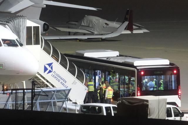 25 August 2026, Saxony, Schkeuditz: A bus carrying men, escorted by federal police officers, is parked next to an airplane at Leipzig-Halle Airport. The federal police used a chartered plane to transport Afghans subject to deportation back to their country of origin. Photo: Sebastian Willnow/dpa