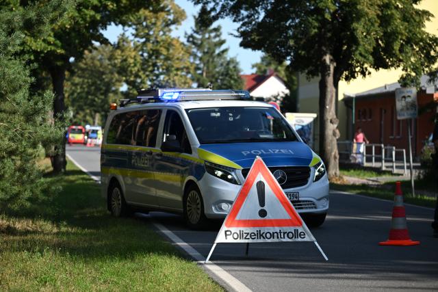 27 August 2026, Brandenburg, Gosen-Neu-Zittau: A police patrol car is parked on the street near a school in Gosen-Neu Zittau, where a woman and a man were killed in a violent incident. Photo: Britta Pedersen/dpa