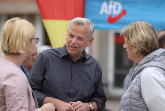 29 August 2026, Mecklenburg-Western Pomerania, Schwerin: Leif-Erik Holm (AfD), a candidate for minister-president, is standing at his party's information booth on Marienplatz in Schwerin, chatting with passersby. Photo: Danny Gohlke/dpa