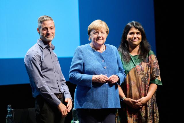 29 August 2026, Berlin: Former German Chancellor Angela Merkel (C) stands between Saba-Nur Cheema (R), political scientist, journalist, and advisor to the federal government on Islamophobia, and Meron Mendel, an Israeli-German educator, journalist, professor, and director of the Anne Frank Educational Center, at the Haus der Berliner Festspiele. The discussion is part of the "Reflexe & Reflexionen" theme days organized by the Berliner Festspiele. Photo: Annette Riedl/dpa