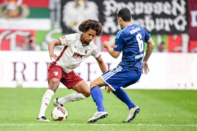 30 August 2026, Bavaria, Augsburg: Augsburg's Han-Noah Massengo (L) in action against Schalke's Ron Schallenberg during the German Bundesliga soccer match between FC Augsburg and FC Schalke 04 at the WWK-Arena. Photo: Harry Langer/dpa - IMPORTANT NOTICE: Bundesliga and DFB regulations prohibit any use of photographs as image sequences and/or quasi-video.