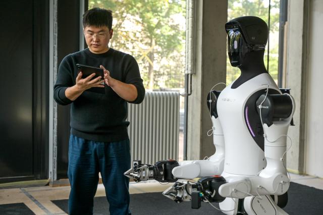 01 September 2026, Saxony-Anhalt, Halle / Saale: Ronnie Hong programs a humanoid robot at the Robo Innovation Lab of Doegel GmbH. The lab, opened in collaboration with the Halle Technology and Startup Center, is the first facility of its kind in central Germany. Photo: Heiko Rebsch/dpa
