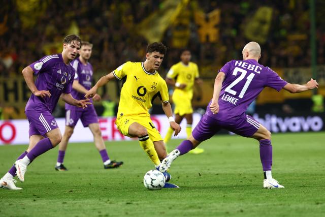 01 September 2026, Hamburg: Borussia Dortmund's Samuele Inacio (C) and HEBC's Fabian Lemke battle for the ball during the German Cup (DFB Pokal) first round soccer match between HEBC and Borussia Dortmund at the Volksparkstadion. Photo: Christian Charisius/dpa - IMPORTANT NOTICE: Bundesliga and DFB regulations prohibit any use of photographs as image sequences and/or quasi-video.