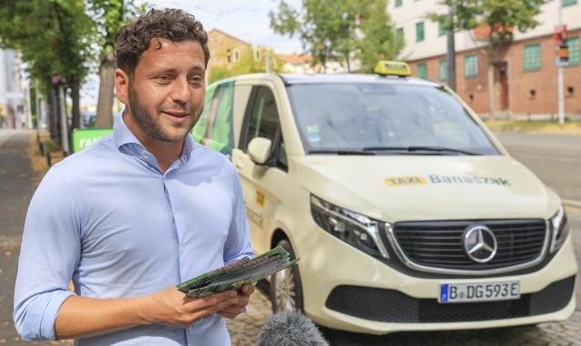 02 September 2026, Saxony-Anhalt, Halle (Saale): Felix Banaszak (Alliance 90/The Greens), federal chairman, stands in front of his "Taxi Banaszak" at the start of the "100-Hour Final Sprint-100,000 Conversations." Photo: Jan Woitas/dpa