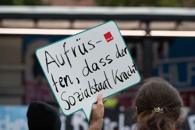 03 September 2026, Saxony, Dresden: A person is holding a sign that reads "Arms up-bring down the welfare state" at a demonstration against cuts to social services, education, public transportation, and culture. The Alliance Against Cuts, together with labor unions and the Left Party, had called for the protest. Photo: Katharina Kausche/dpa