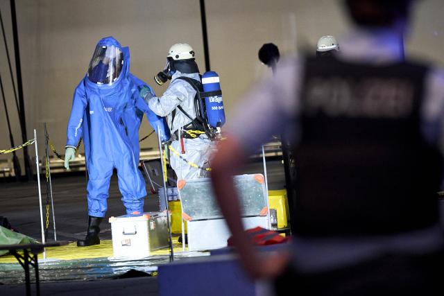 03 September 2026, Brandenburg, Schönefeld: A firefighter wearing a chemical protection suit is being decontaminated by a colleague outside Terminal 1 at BER Airport, which was partially evacuated due to a potentially hazardous substance. Photo: Michael Ukas/dpa