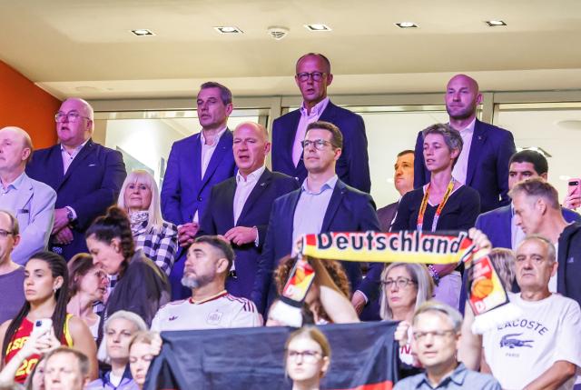 04 September 2026, Berlin: German Chancellor Friedrich Merz (C-R) and German Minister of State for Volunteer Work and Sports Ronald Rauhe (R) sing the national anthem before the FIBA Women's Basketball World Cup preliminary round Group A basketball match between Spain and Germany. Photo: Andreas Gora/dpa