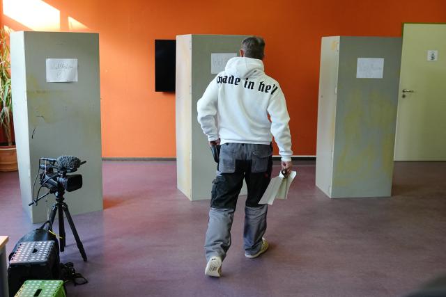 06 September 2026, Saxony-Anhalt, Tangermünde: A voter walks to the voting booths with her ballots at a polling station. A video camera is set up beside the booths for media coverage. Saxony-Anhalt elects a new state parliament on Sunday. Photo: Kay Nietfeld/dpa