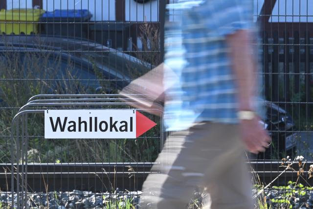 06 September 2026, Saxony-Anhalt, Wernigerode: A person walks past a sign pointing to a polling station. Saxony-Anhalt elects a new state parliament on Sunday. Photo: Julian Stratenschulte/dpa