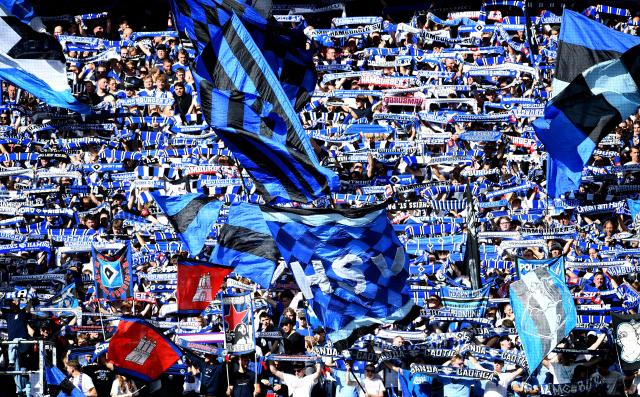 06 September 2026, Hamburg: Hamburg fans wave flags and holding scarves during the German Bundesliga soccer match between Hamburger SV and FSV Mainz 05 at Volksparkstadion. Photo: Daniel Bockwoldt/dpa - WICHTIGER HINWEIS: Gemäß den Vorgaben der Bundesliga bzw. des DFB Deutscher Fußball-Bund ist es untersagt, in dem Stadion und/oder vom Spiel angefertigte Fotoaufnahmen in Form von Sequenzbildern und/oder videoähnlichen Fotostrecken zu verwerten bzw. verwerten zu lassen.