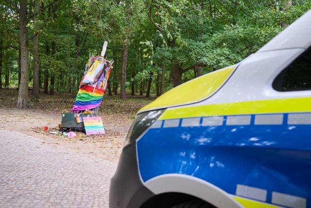 06 September 2026, Berlin: The damaged memorial tree commemorating the Berlin Christopher Street Day
(CSD) attack stands next to a police car. The metal protective barrier and the tree were pried out of the ground at one point. Photo: Annette Riedl/dpa
