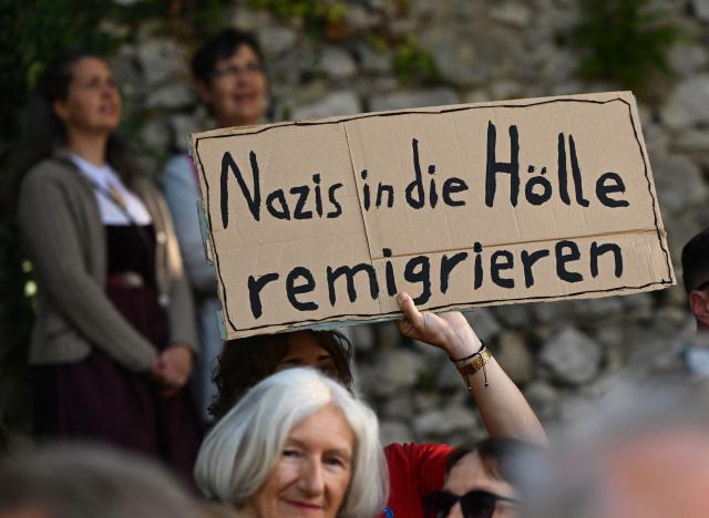 07 September 2026, Bavaria, Abensberg: Opponents of the AfD stand at the entrance to the Schlossgarten during the political morning beer gathering at the Gillamoos folk festival, holding a sign reading "Send the Nazis back to hell." The Gillamoos is one of Lower Bavaria's largest and oldest folk festivals and traditionally features political events involving the parties. Photo: Sven Hoppe/dpa
